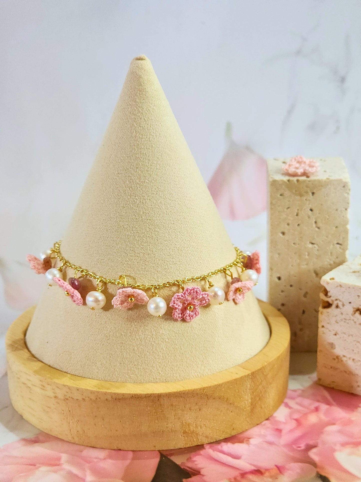 Handcrafted micro-crochet Sakura blossoms flanked by natural 5-6mm freshwater pearls on an 14K gold-plated bracelet close up.