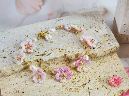 Handcrafted pink-white micro‑crochet Sakura blossoms, flanked by 5-6mm natural Baroque pearls. 14K gold-plated bracelet close up.